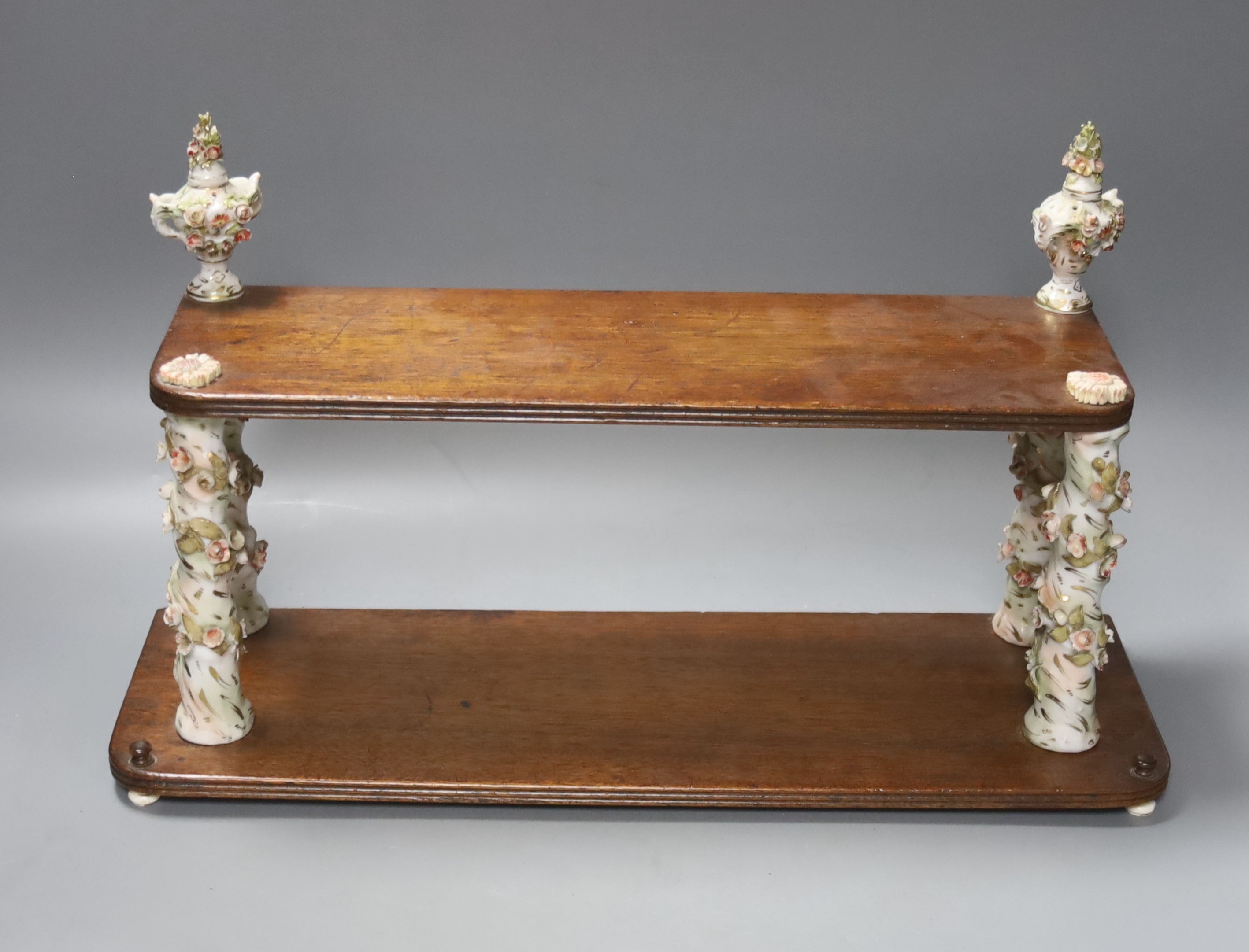 A Continental mahogany and floral encrusted porcelain two tier wall shelf